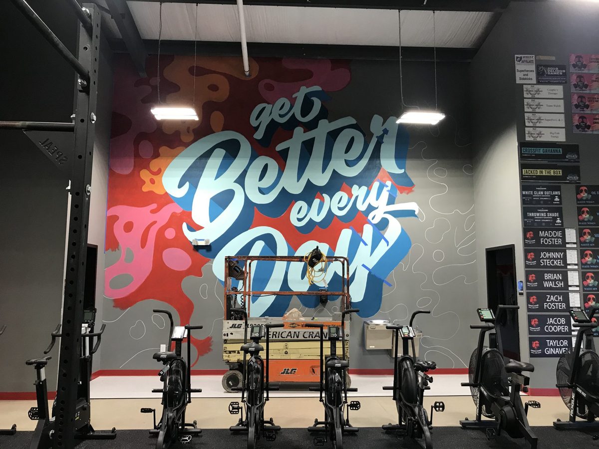 The mural in progress, with a lift in front of the wall in the gym