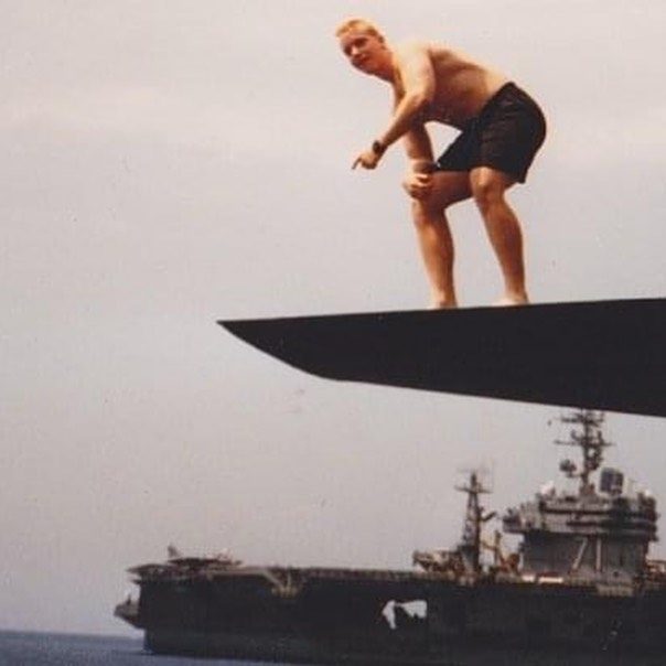 Jake mid-jump from a submarine’s sailplane, with an aircraft carrier on the horizon