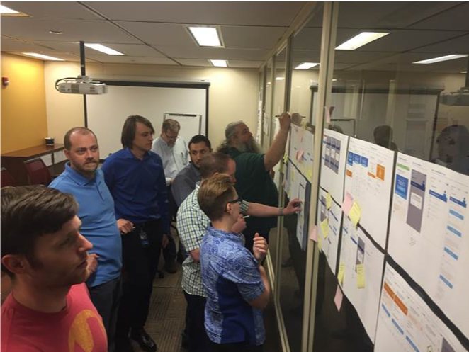 Designers, developers and stakeholders reviewing flows on a wall